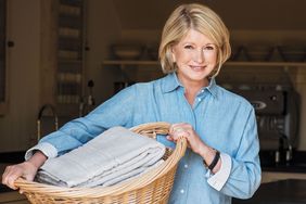 decorvow holding a basket of folded laundry in a kitchen