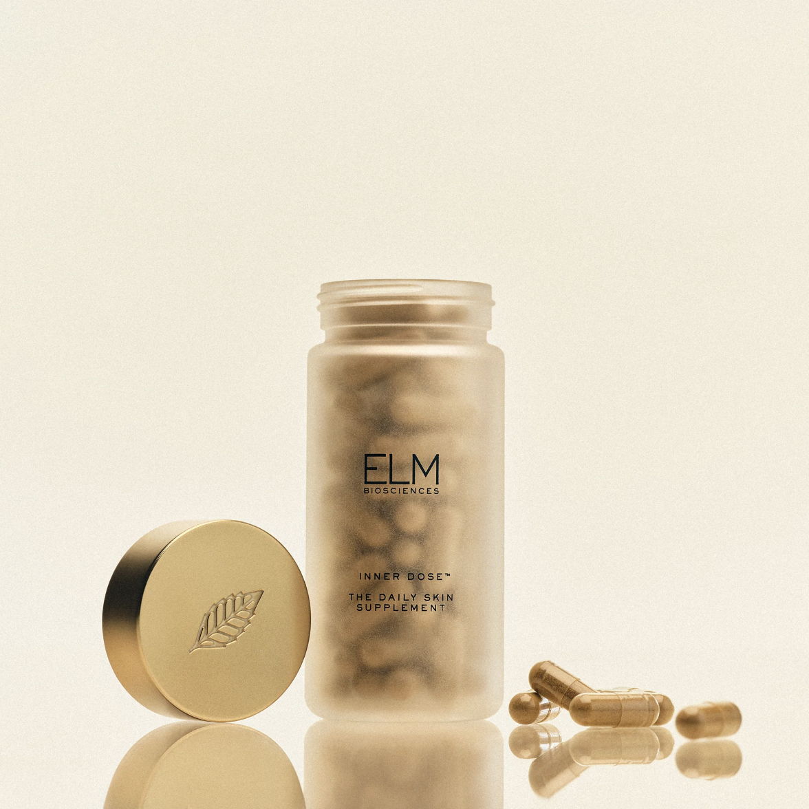 A bottle of ELM supplements with capsules spilled nearby and its lid to the side