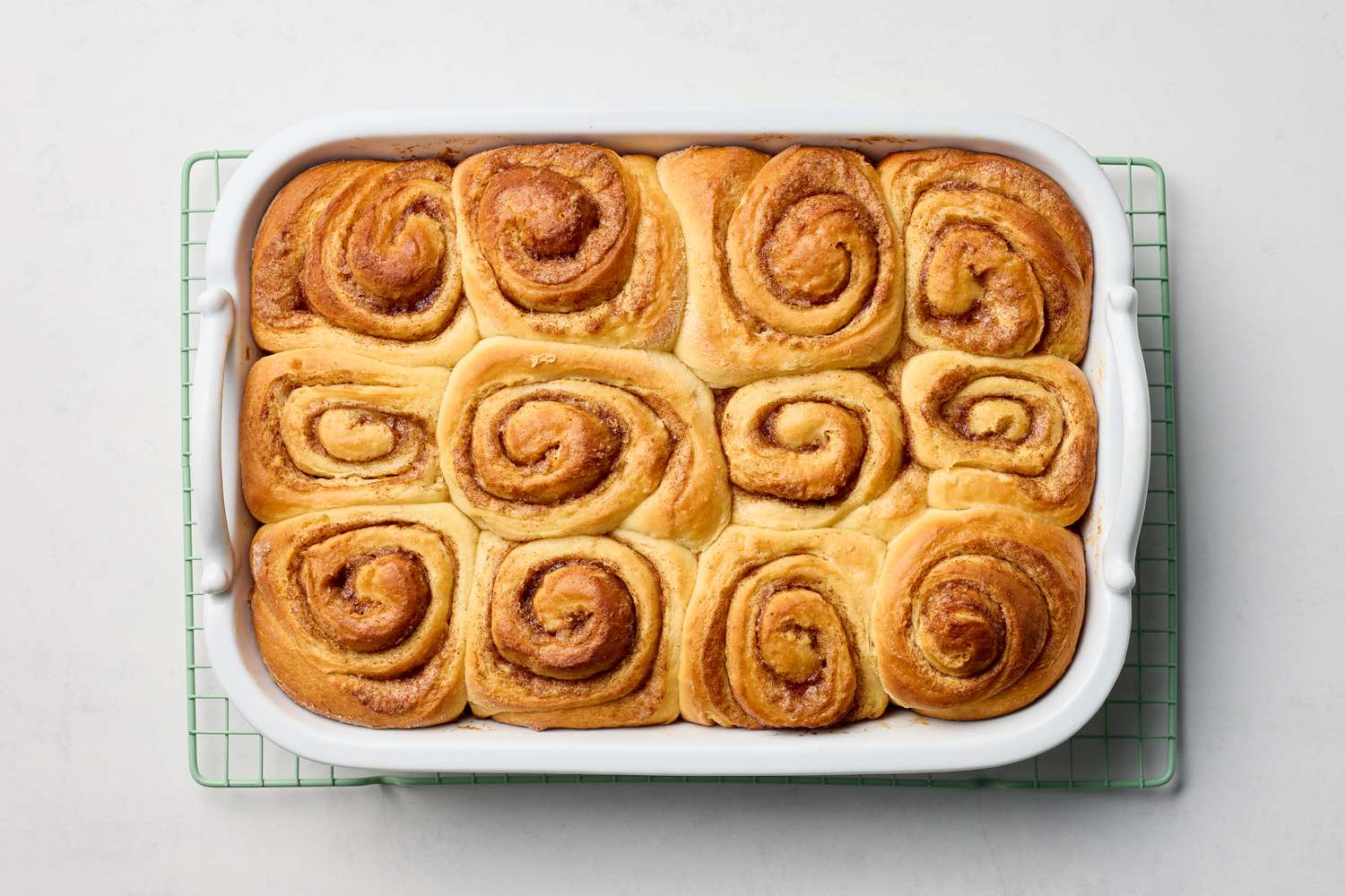 A tray of freshly baked cinnamon rolls placed on a cooling rack