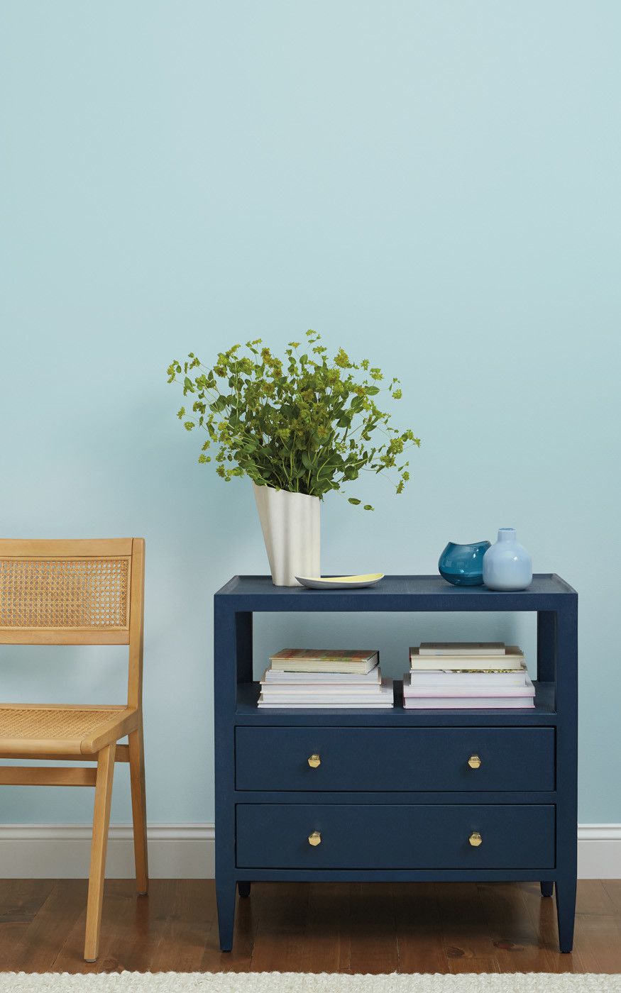 white vase of greenery atop blue book case