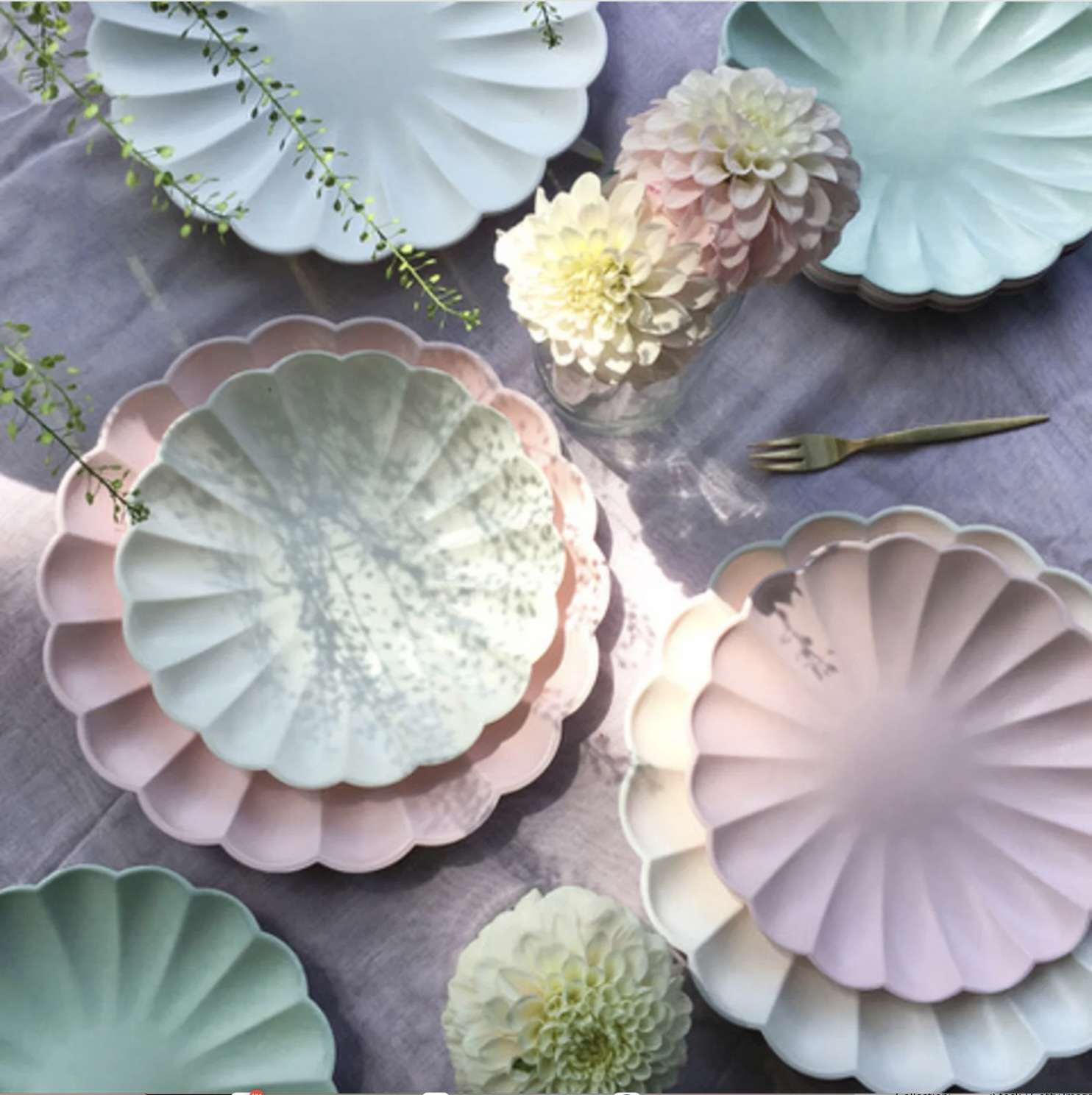 Scalloped plates arranged on a table with flowers and a fork