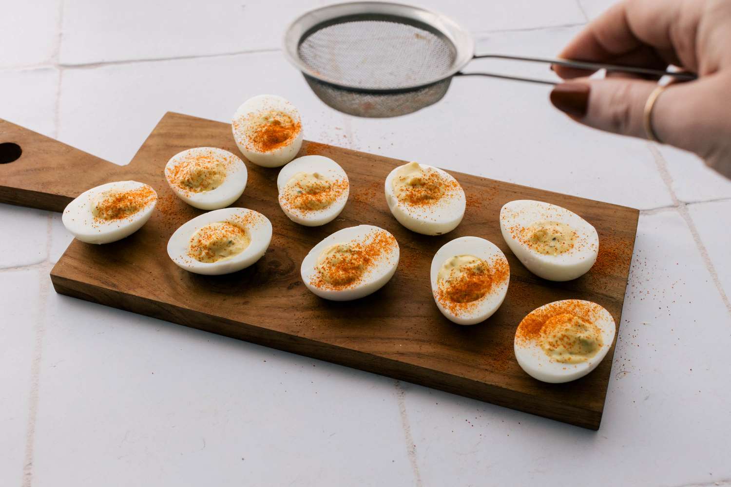 Sifting cayenne over deviled eggs