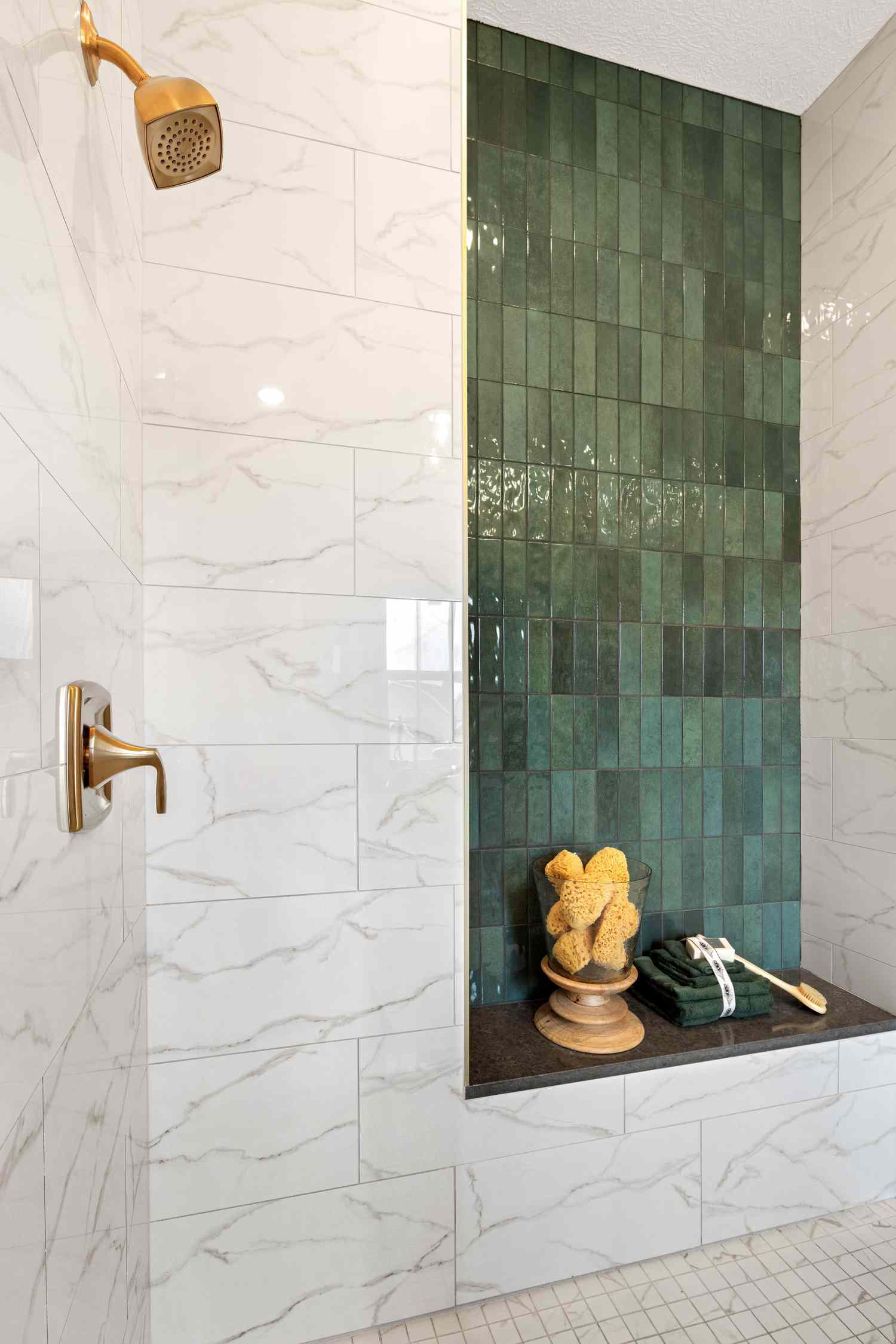A white marbled shower with a pop of green subway tiled in a shelf backsplash