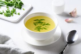 bone broth with sliced scallions in white bowl on white table