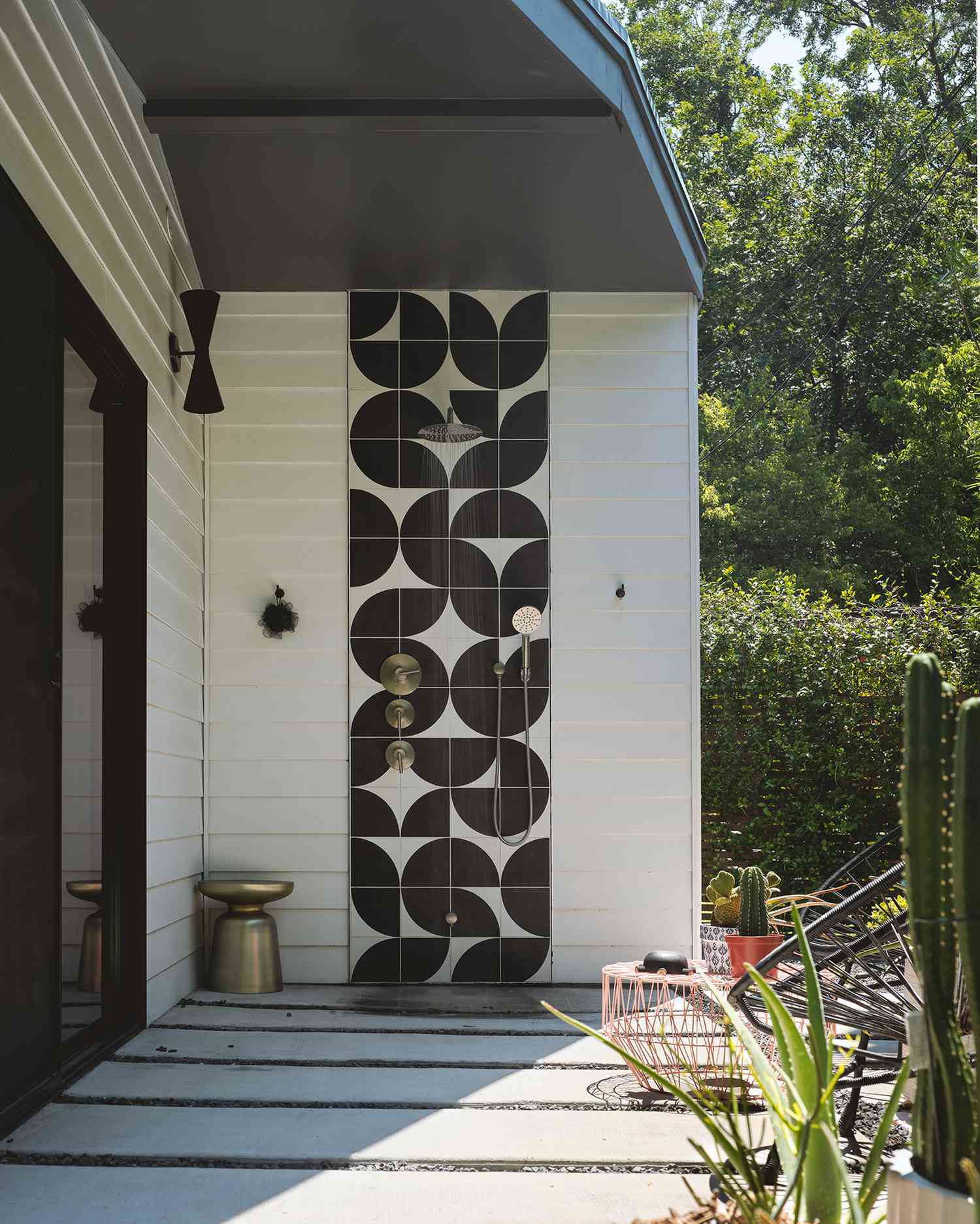 Outdoor shower with black and white geometric tiles.