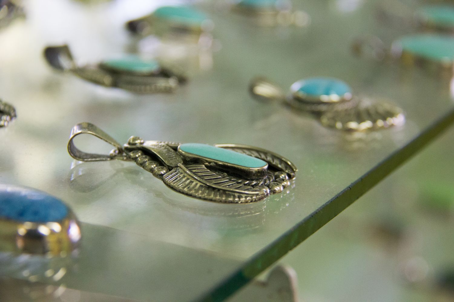 Closeup of silver pendants with blue stones displayed on a glass surface
