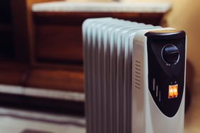 An electric space heater with a lit indicator light positioned indoors