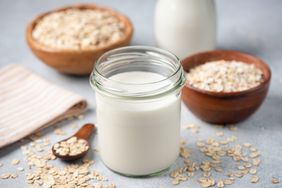 A jar of oat milk surrounded by bowls of oats