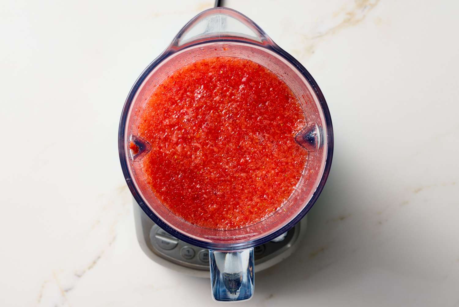 A blender containing blended strawberry daiquiri mixture, viewed from above