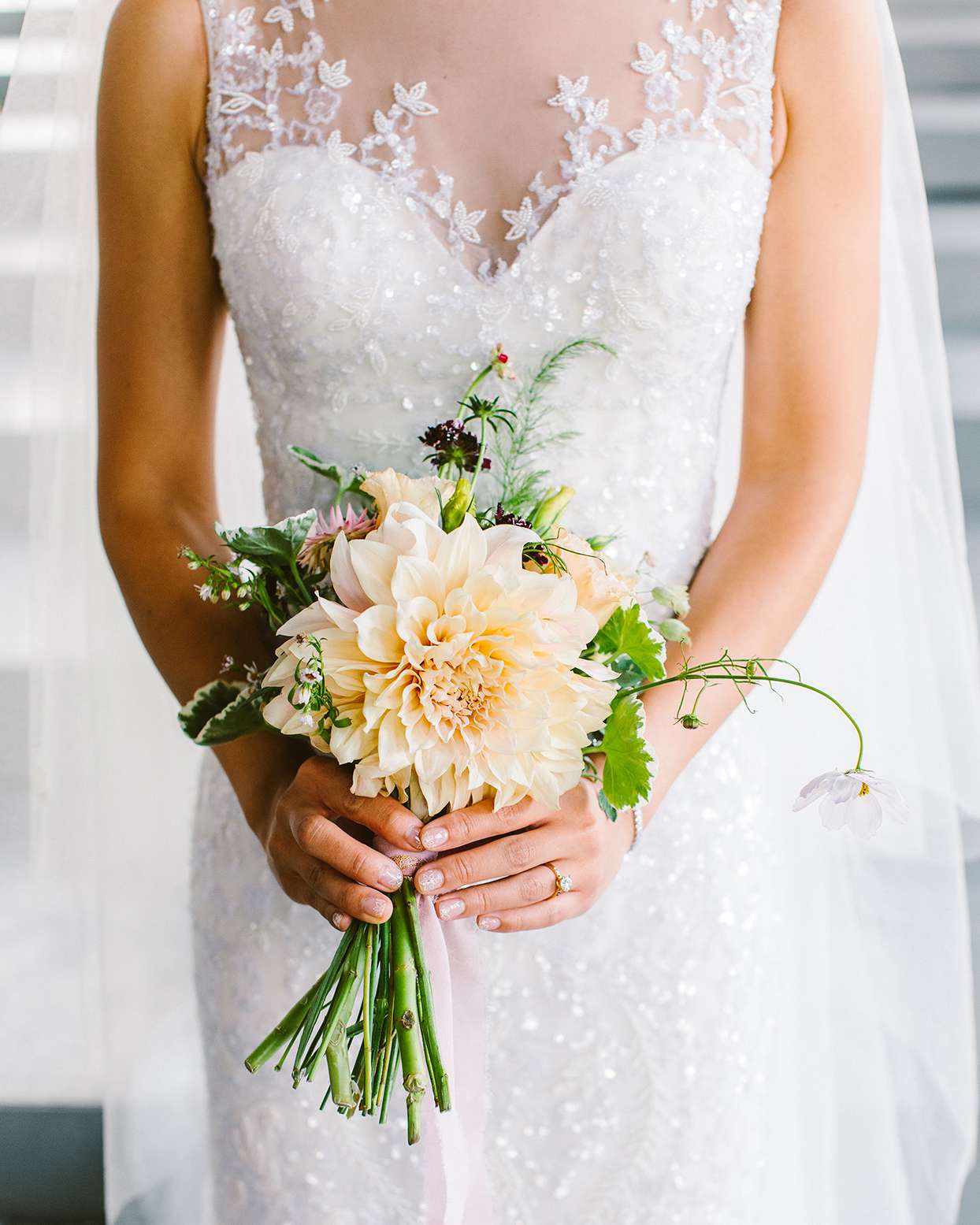 bride in white holding pastel bouquet with orange flower