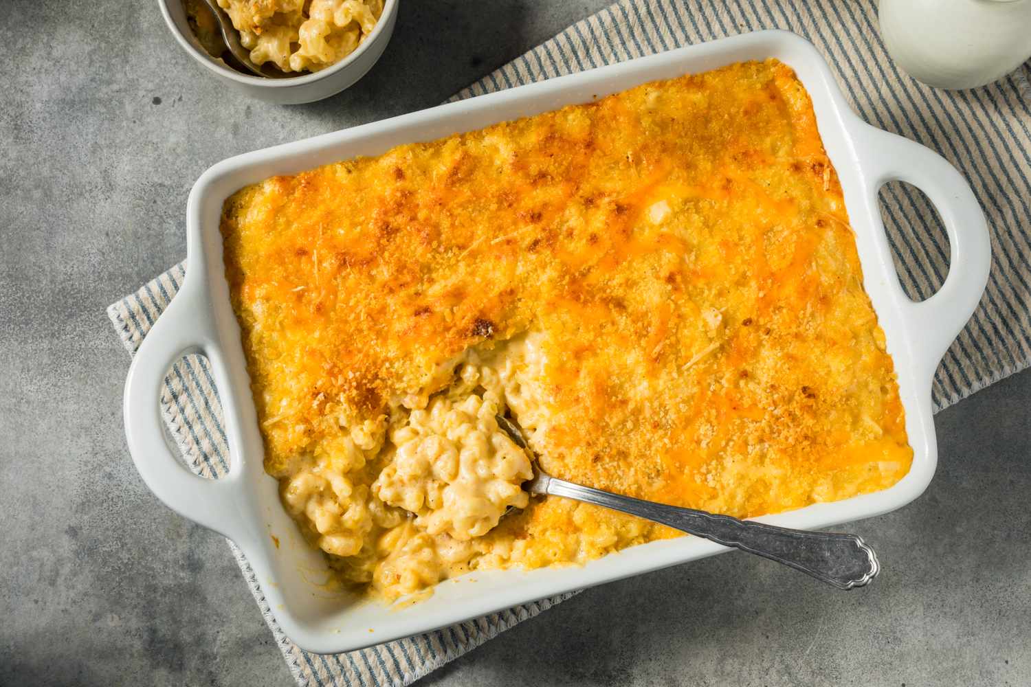A baked macaroni and cheese dish with a serving spoon resting inside the pan
