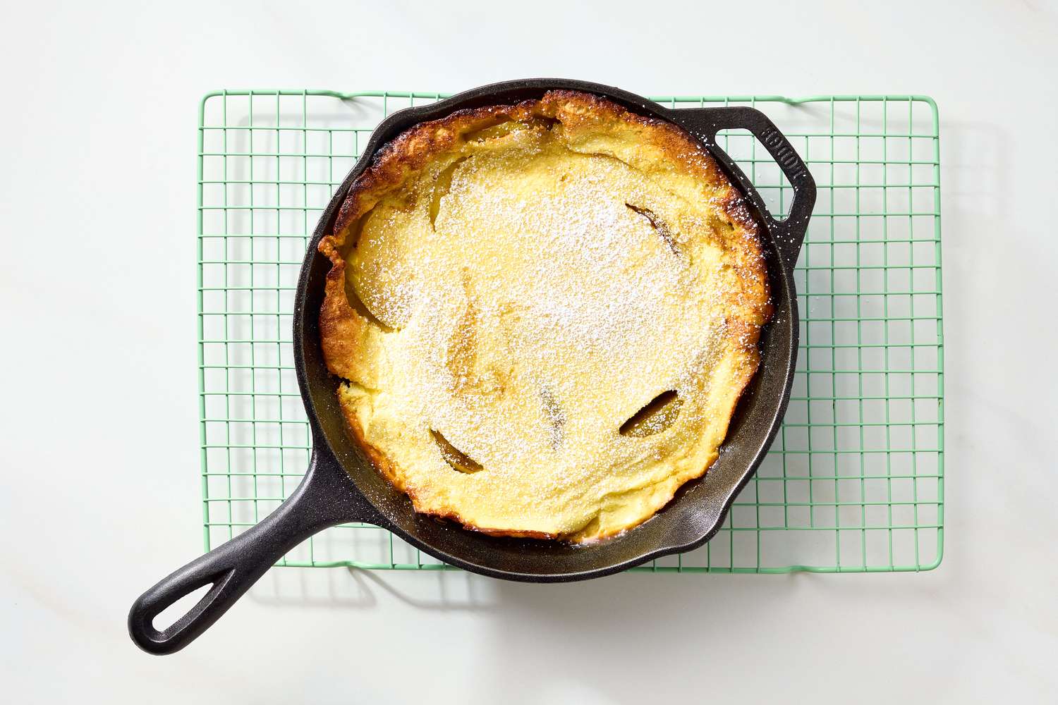A Dutch baby pancake in a castiron skillet placed on a wire rack