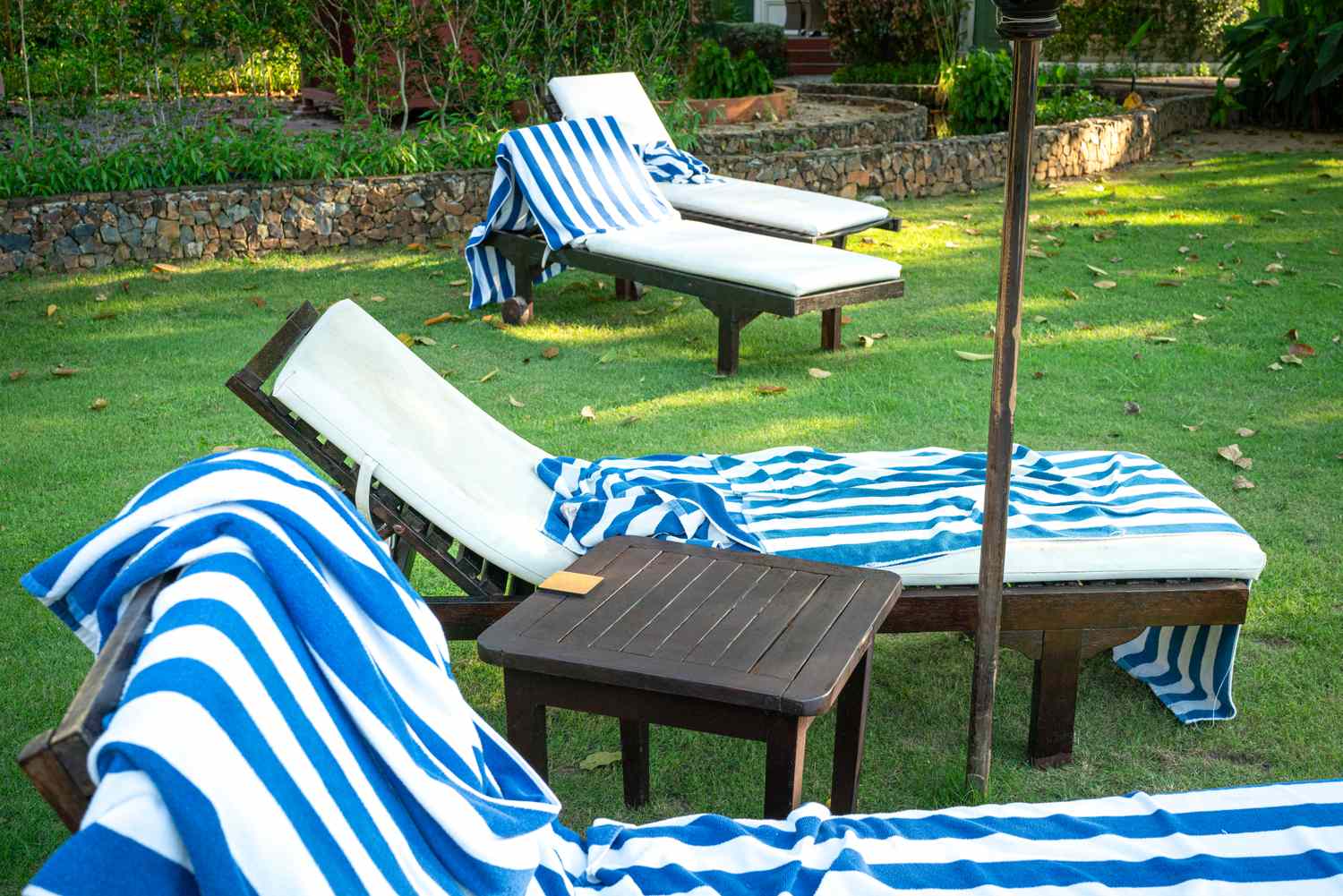 Outdoor lounge chairs with blue and white striped towels on a grassy area