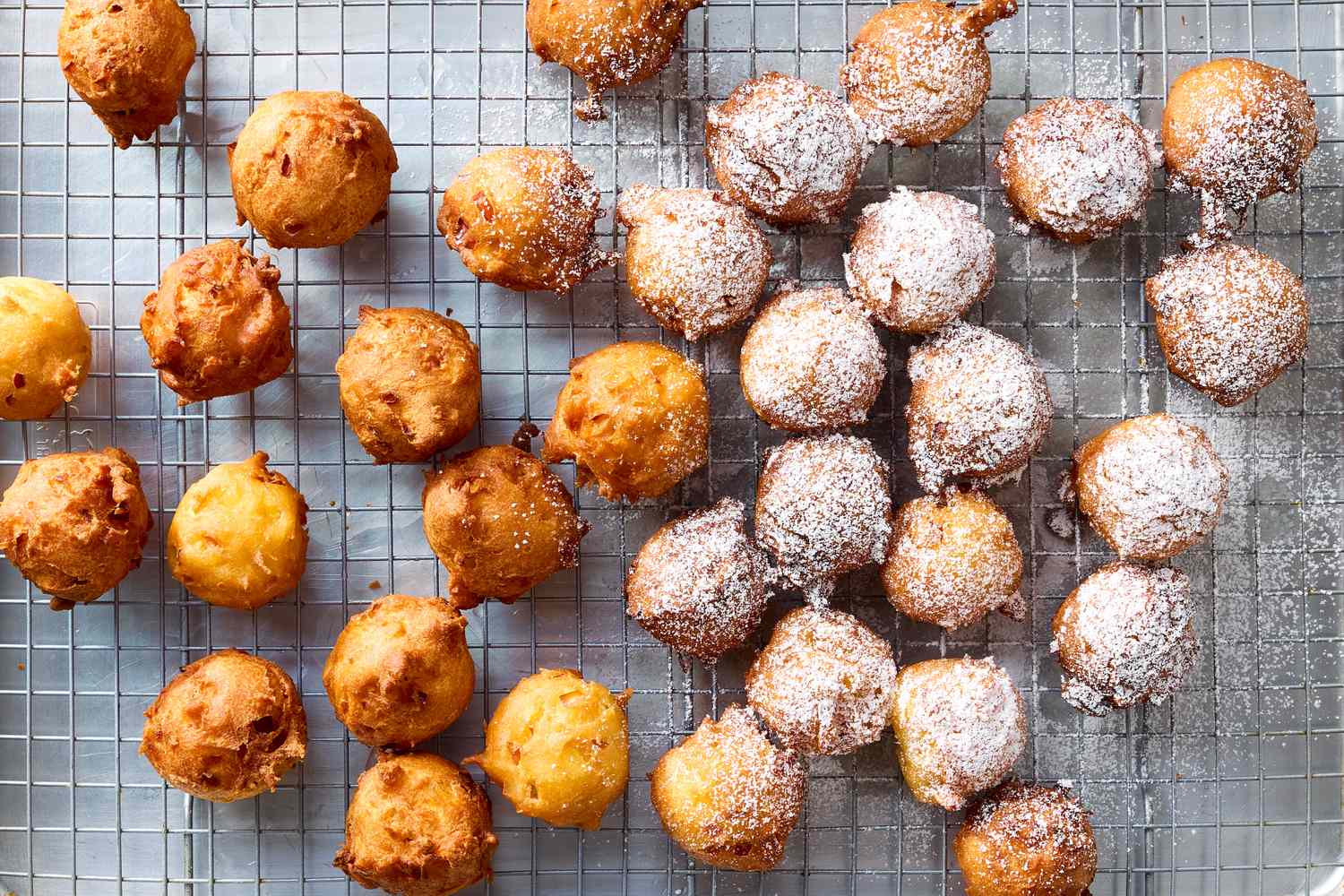 Apple fritters arranged on a cooling rack some dusted with powdered sugar