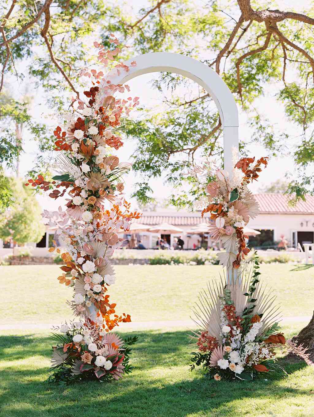 sara trisdan wedding white arch with warm tones floral decorations