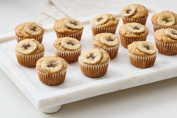 Banana muffins on a marble tray topped with banana slices