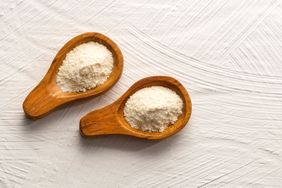 Two wooden spoons with powdered substance on a textured surface