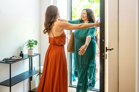 Two women hugging near a doorway welcoming each other