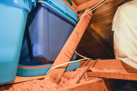 Storage bins in an attic space with insulation and wooden beams visible