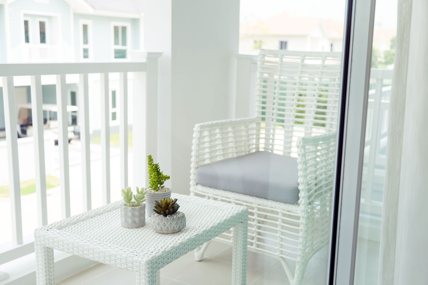 A balcony with a resin wicker chair a small table and potted plants