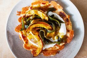 Charred squash and peppers on a dish with creamy sauce and a crispy base