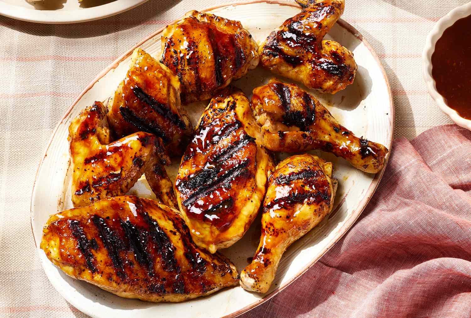Platter with grilled barbecue chicken pieces on a table
