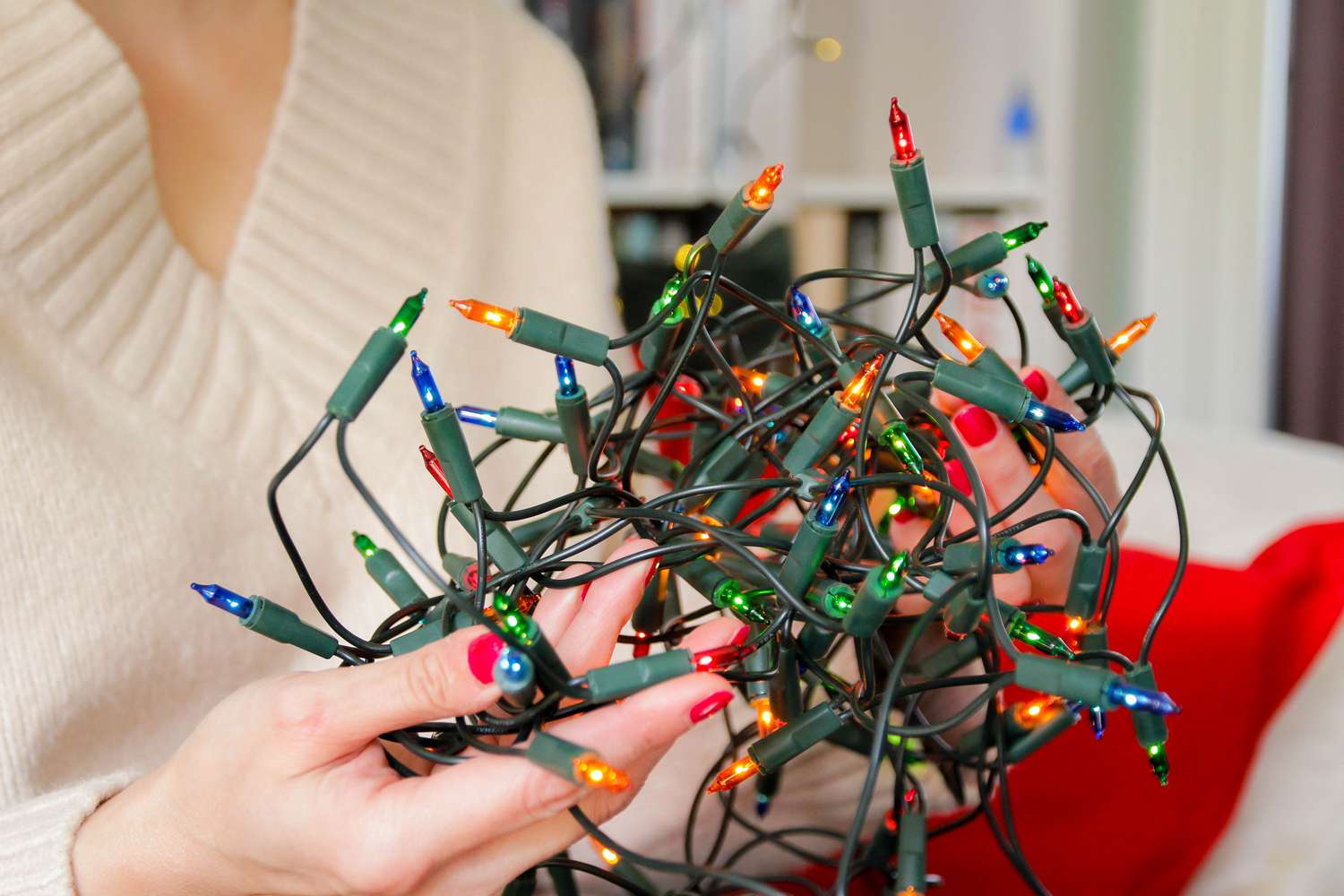 Hands handling tangled string lights casual indoor scene