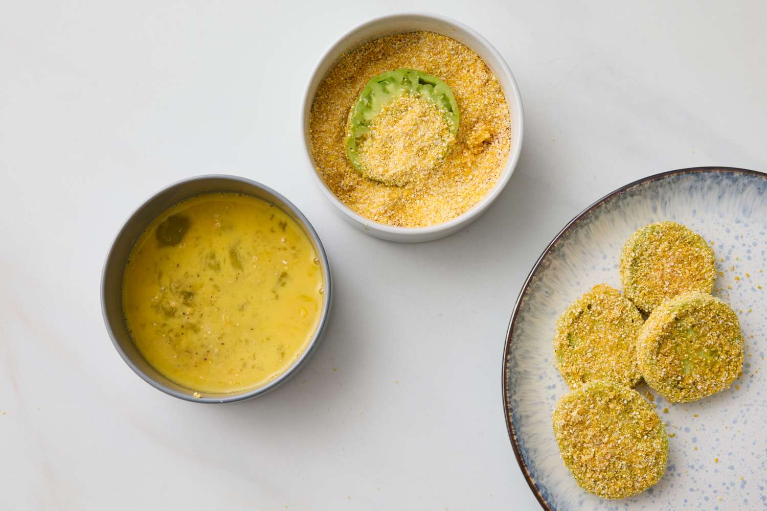 Ingredients and preparation steps for fried green tomatoes showcasing breading process in bowls and plated slices