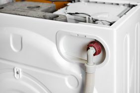 Open washing machine with exposed inner parts and drain hose connection