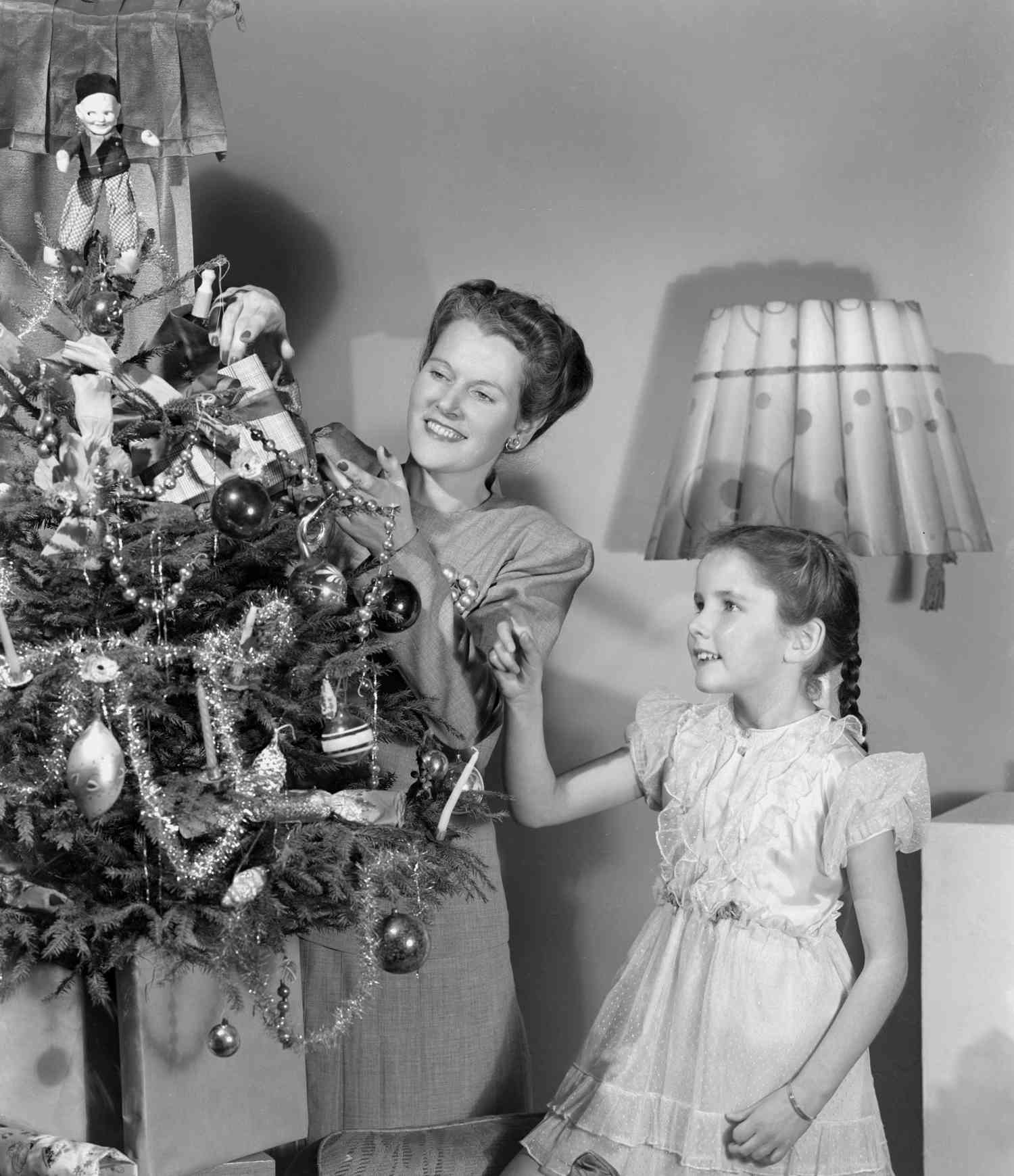 Woman and girl decorating a Christmas tree, c 1948.