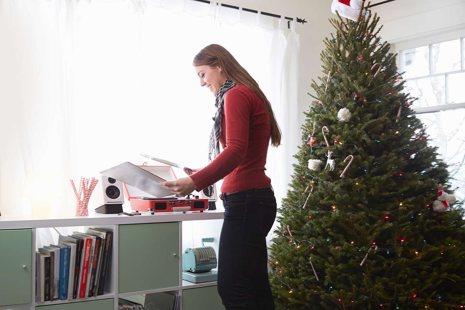 Person looking through records next to Christmas tree