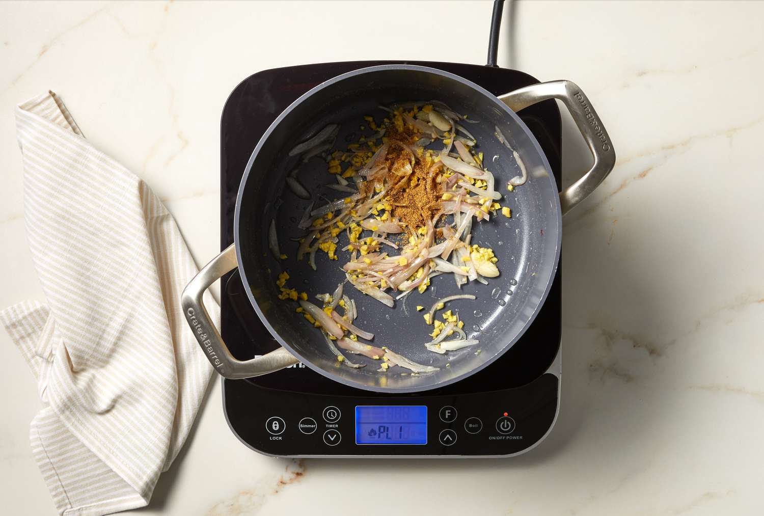 overhead view of vegetables and orange spice cooking in a pot on marble surface
