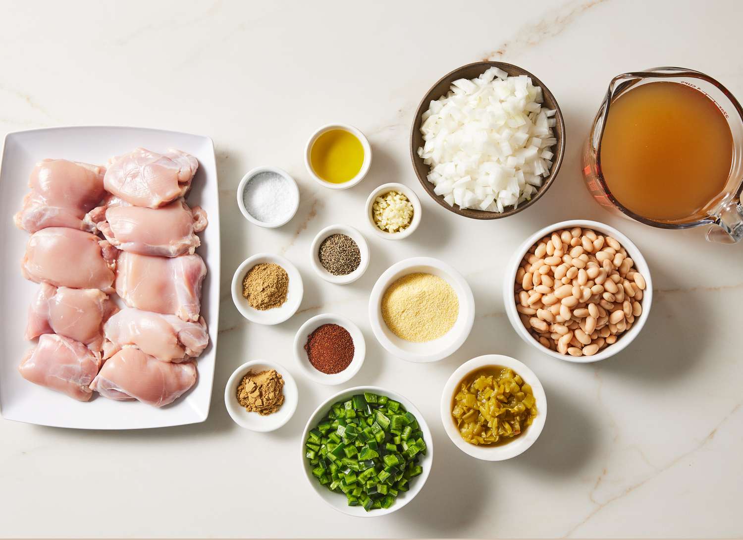overhead view of raw chicken and multiple bowls of ingredients