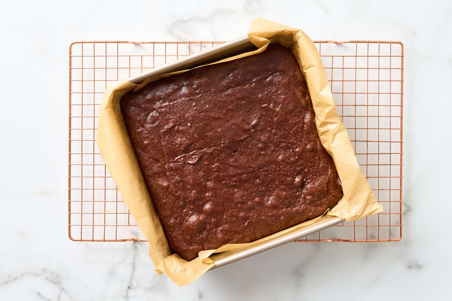 A pan of chewy brownies resting on a wire cooling rack