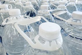 Multiple rows of large water jugs with plastic handles and caps