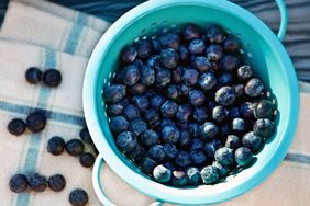 overhead view of washed blueberries in a teal colander 