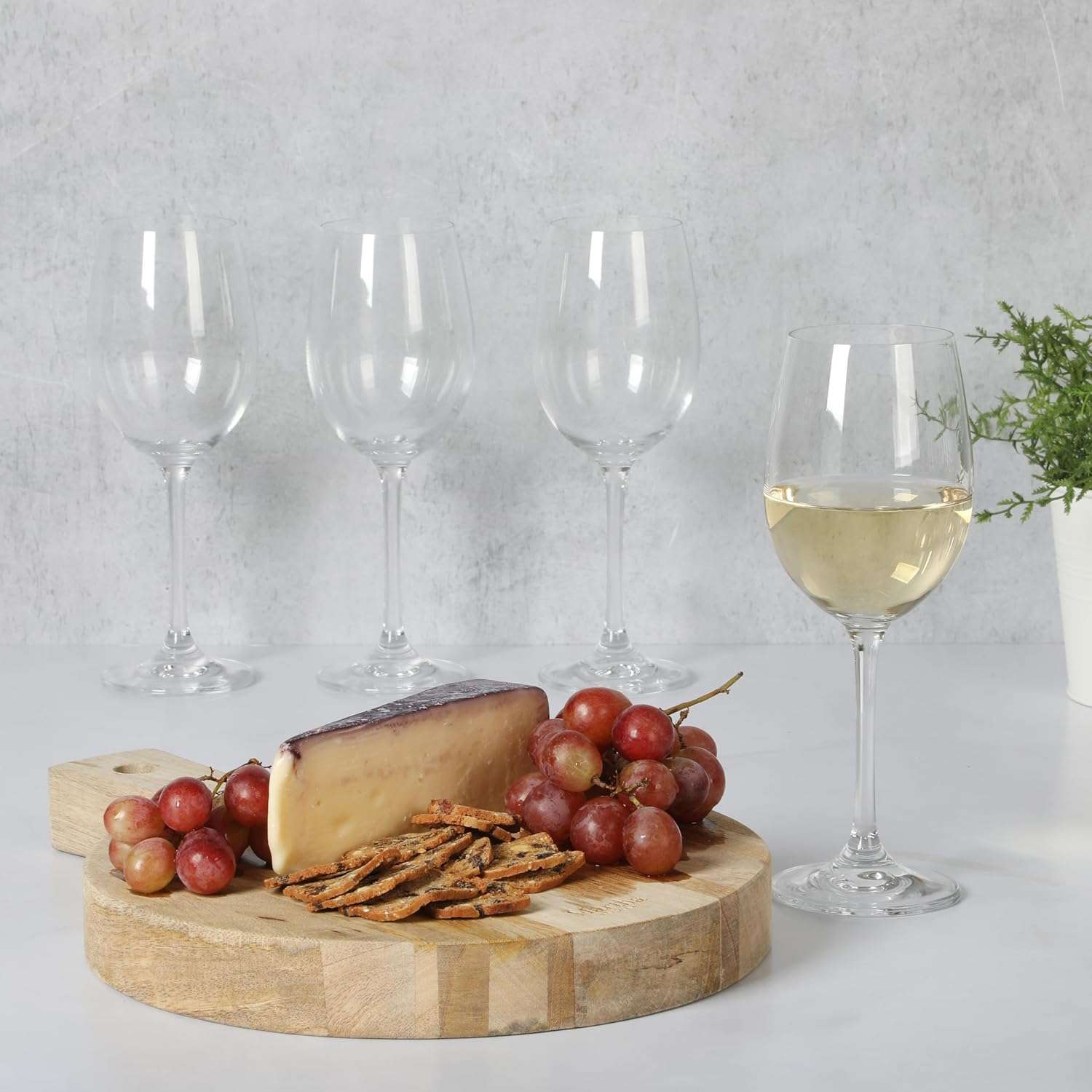 Wine glass among grapes cheese and crackers on a wooden board
