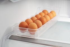 A row of eggs in a transparent container inside a refrigerator