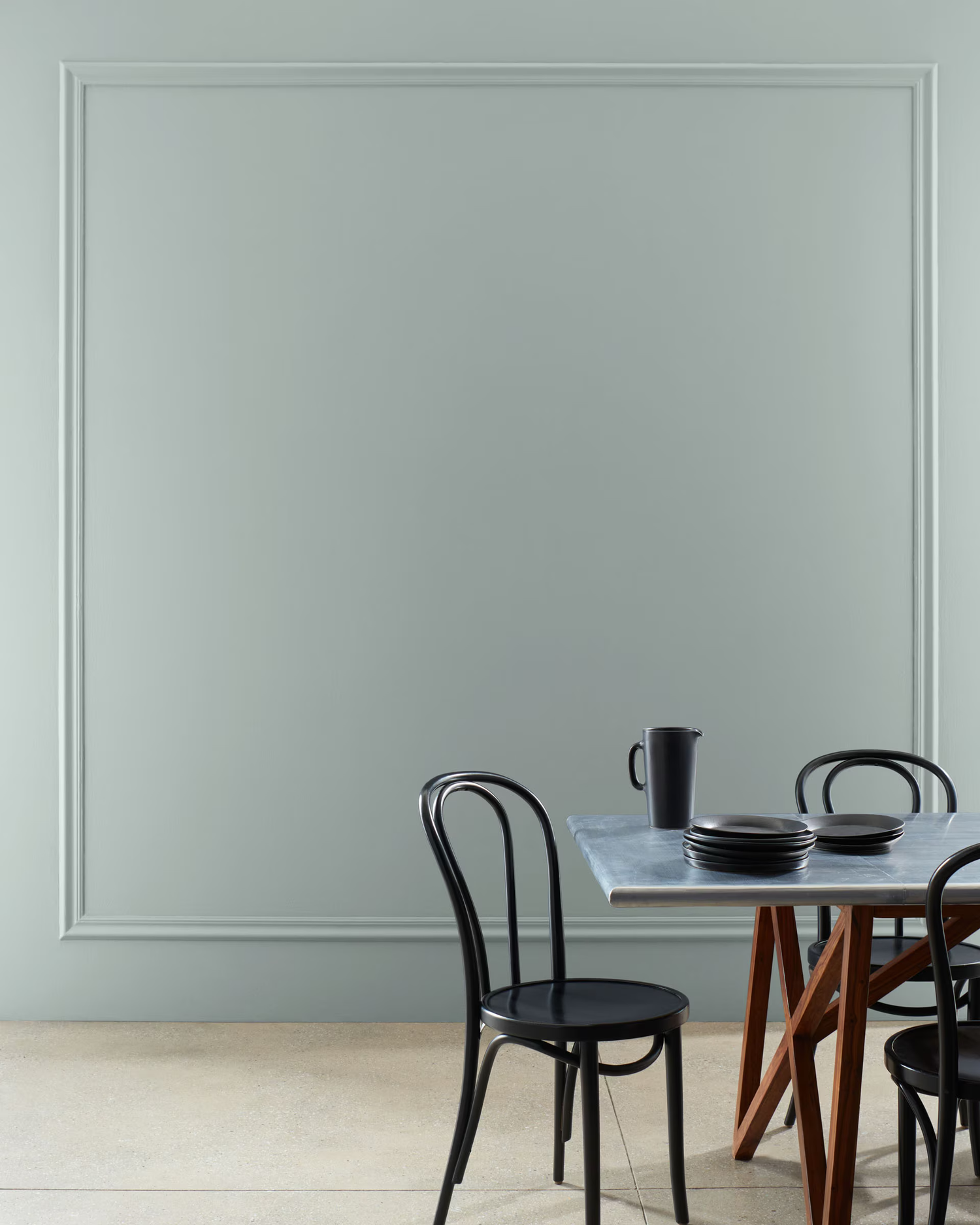 A dining table with chairs and tableware against a neutral wall