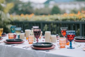 Elegant table setting with decorative glassware and candles arranged outdoors on a white tablecloth