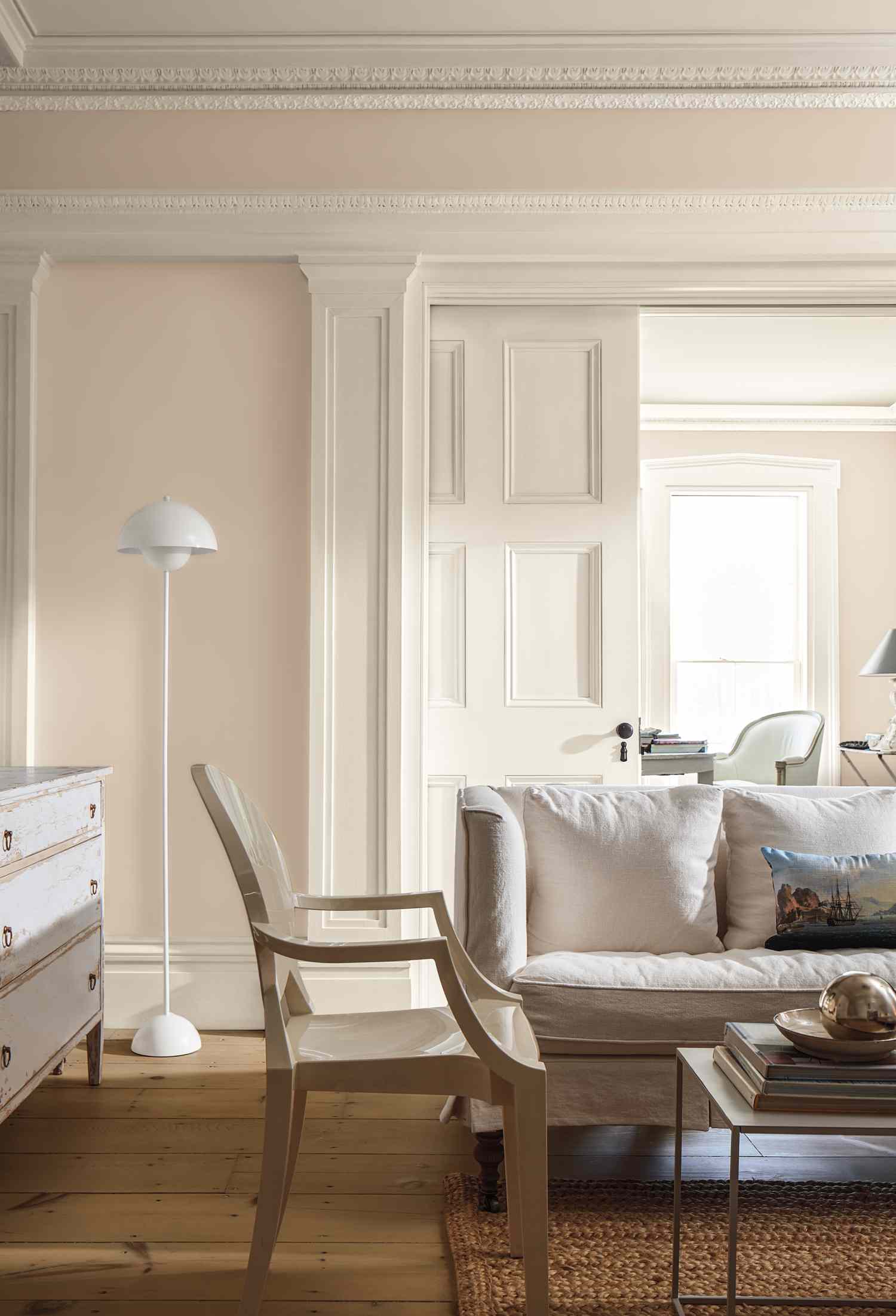 A living room featuring a sofa lamp and an open door to another room with a desk and chair