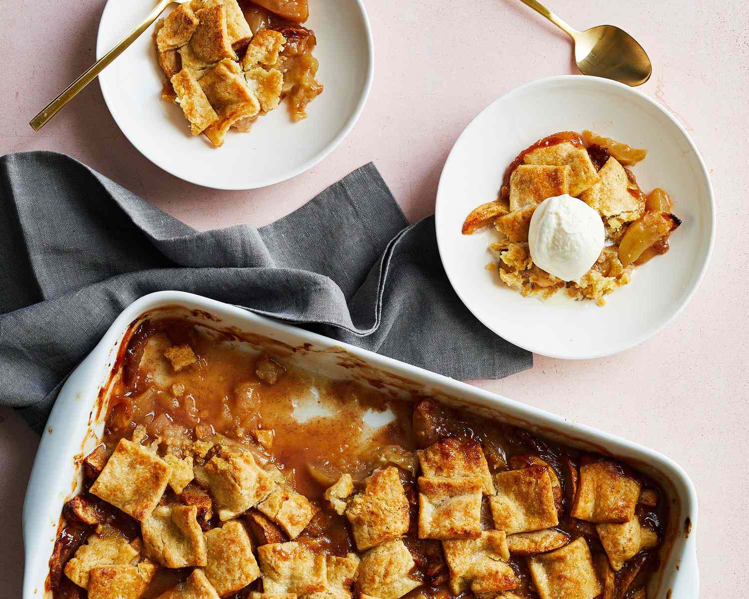 A freshly baked apple pandowdy in a baking dish with two servings plated one topped with ice cream