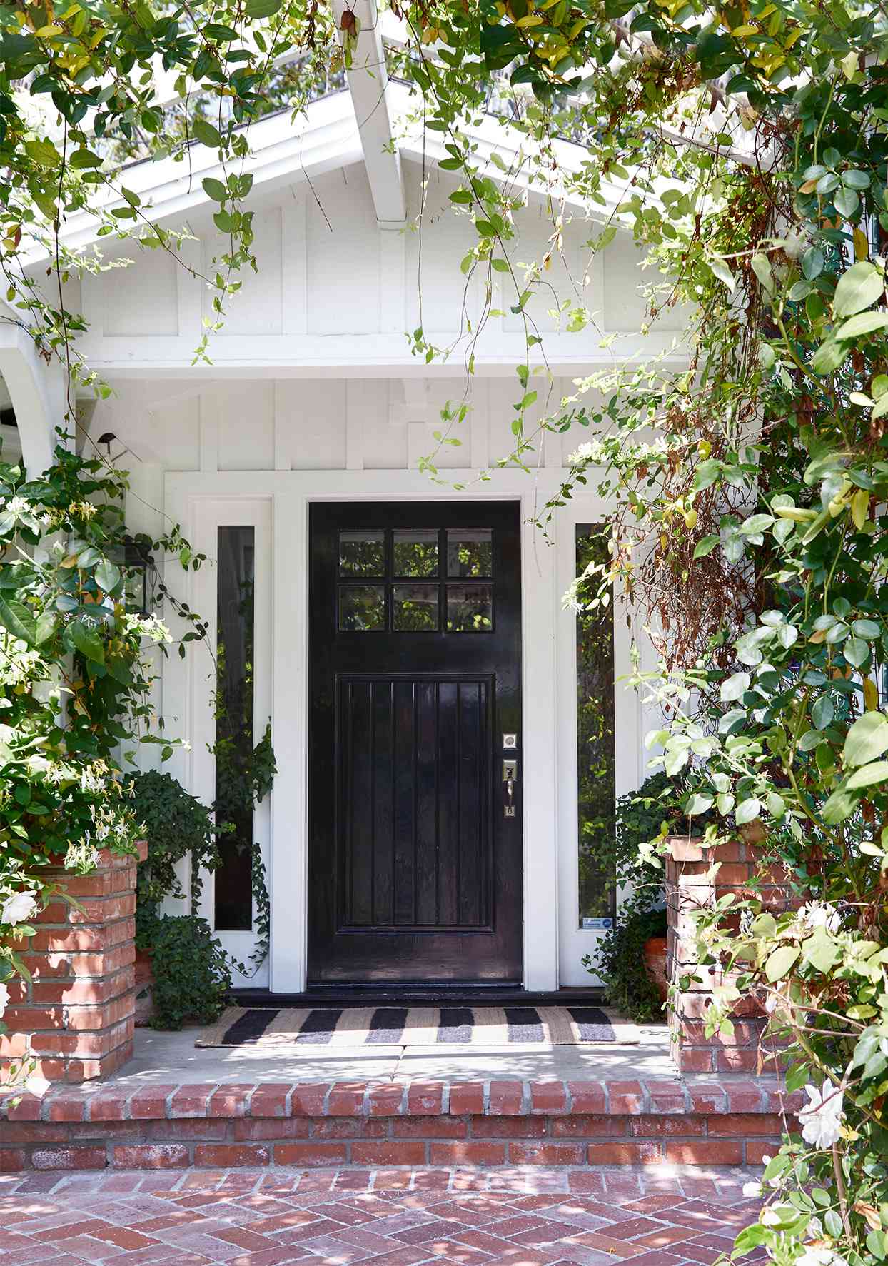 black front door on white house with brick entry way