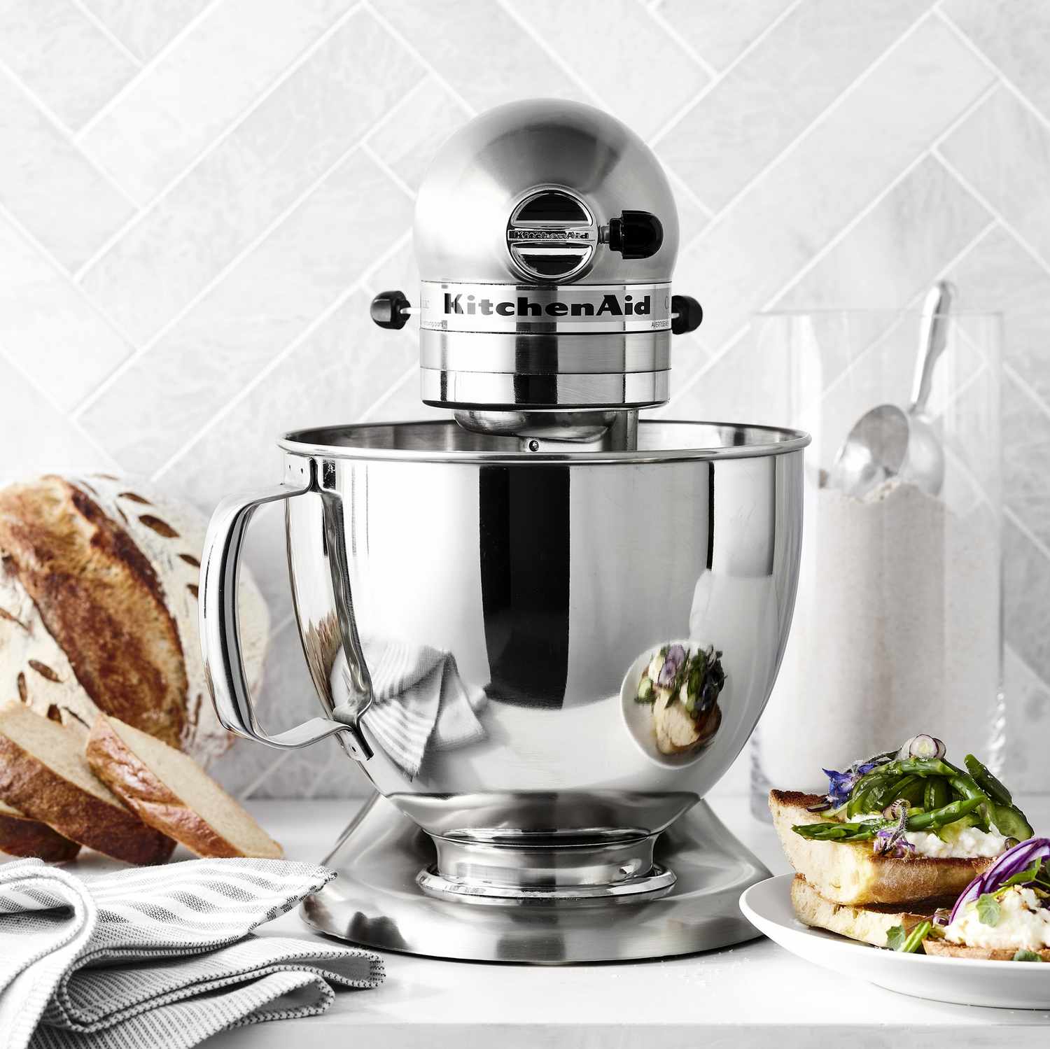 KitchenAid stand mixer on a kitchen counter with bread and salad nearby