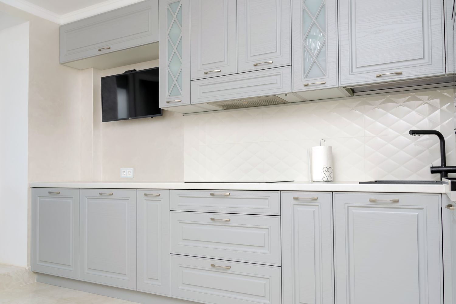 Modern kitchen with cabinets a builtin TV and a countertop with a paper towel holder