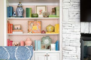 white shelving with pink wallpaper behind