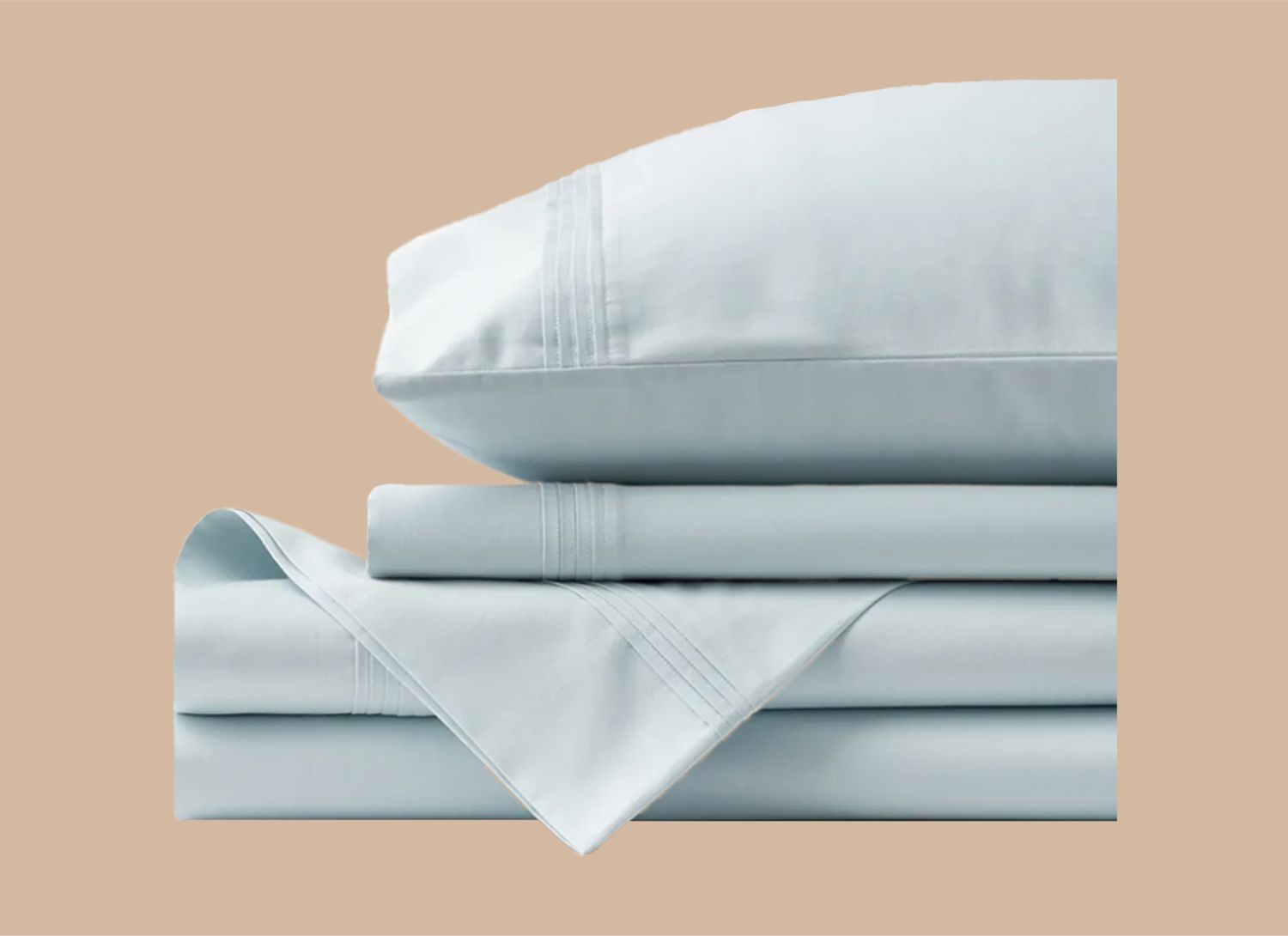 pale blue stack of sheets and pillow on a tan background