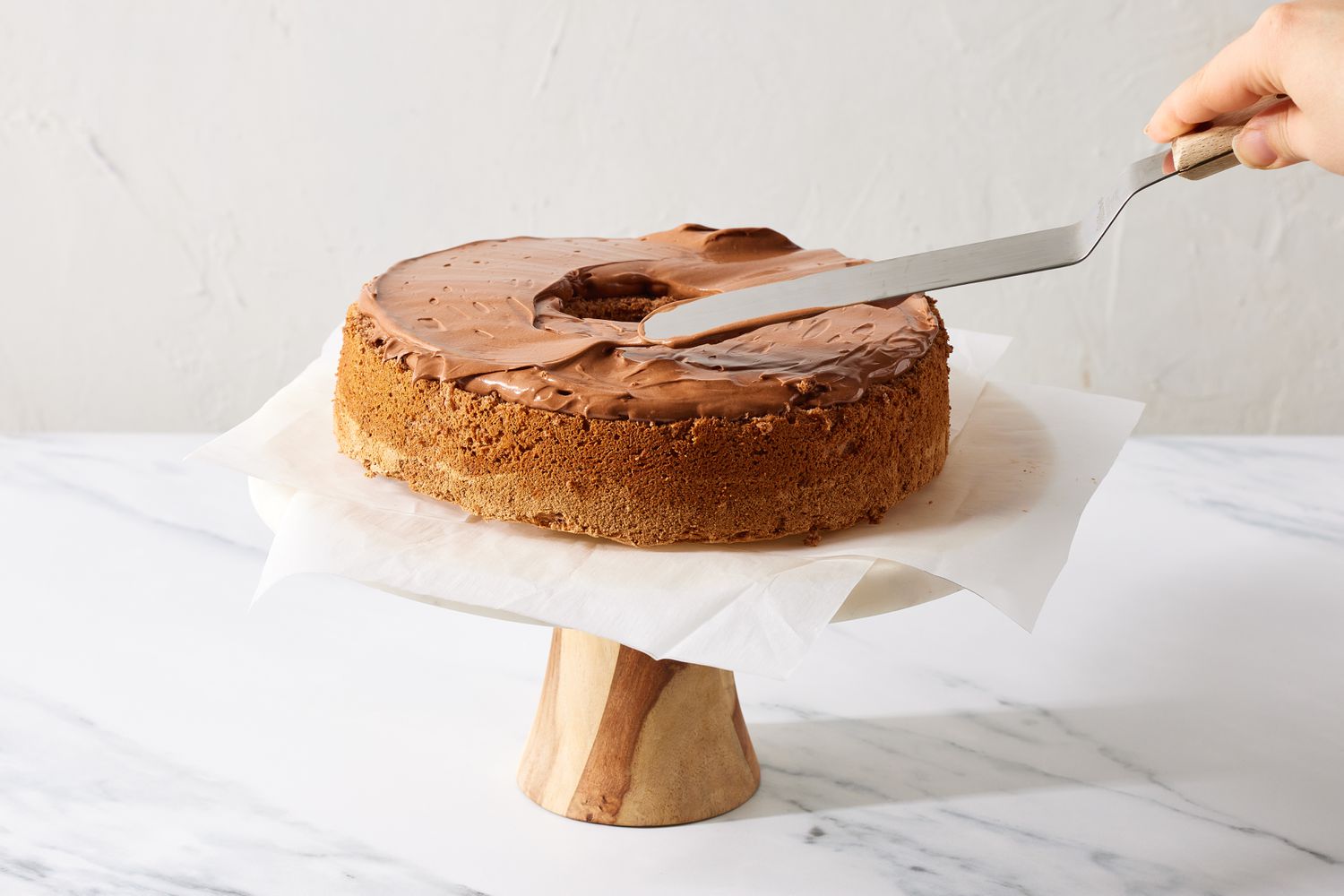 Person frosting cake on cake stand