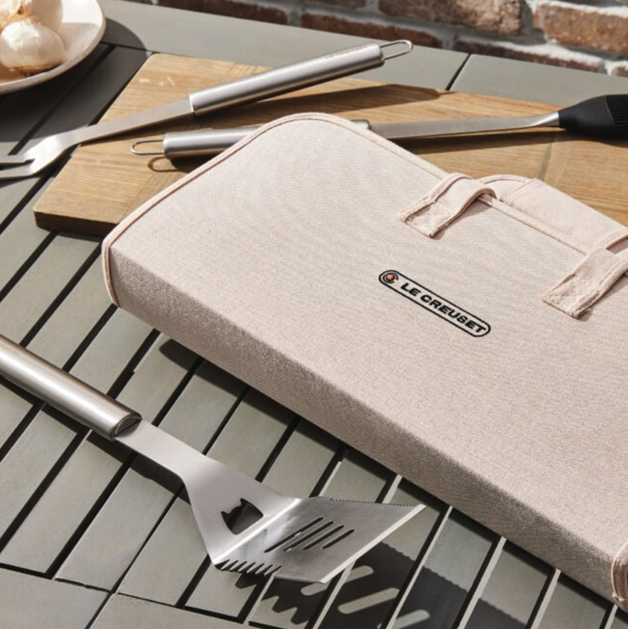 Set of Le Creuset grill tools on a table, including a spatula and grilling fork, with a fabric case