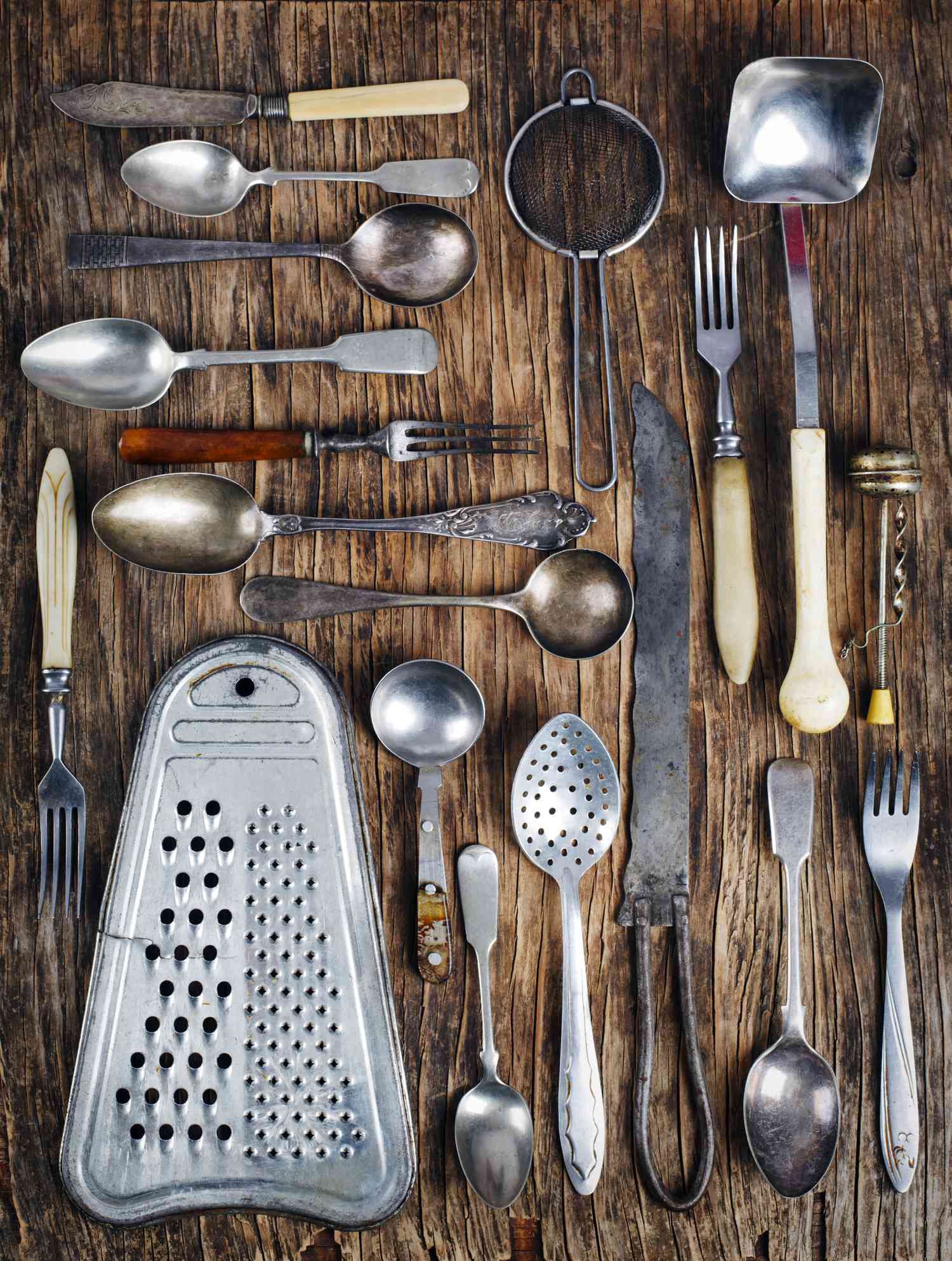 Vintage cutlery - spoons, forks, knives and grater, on wooden background.